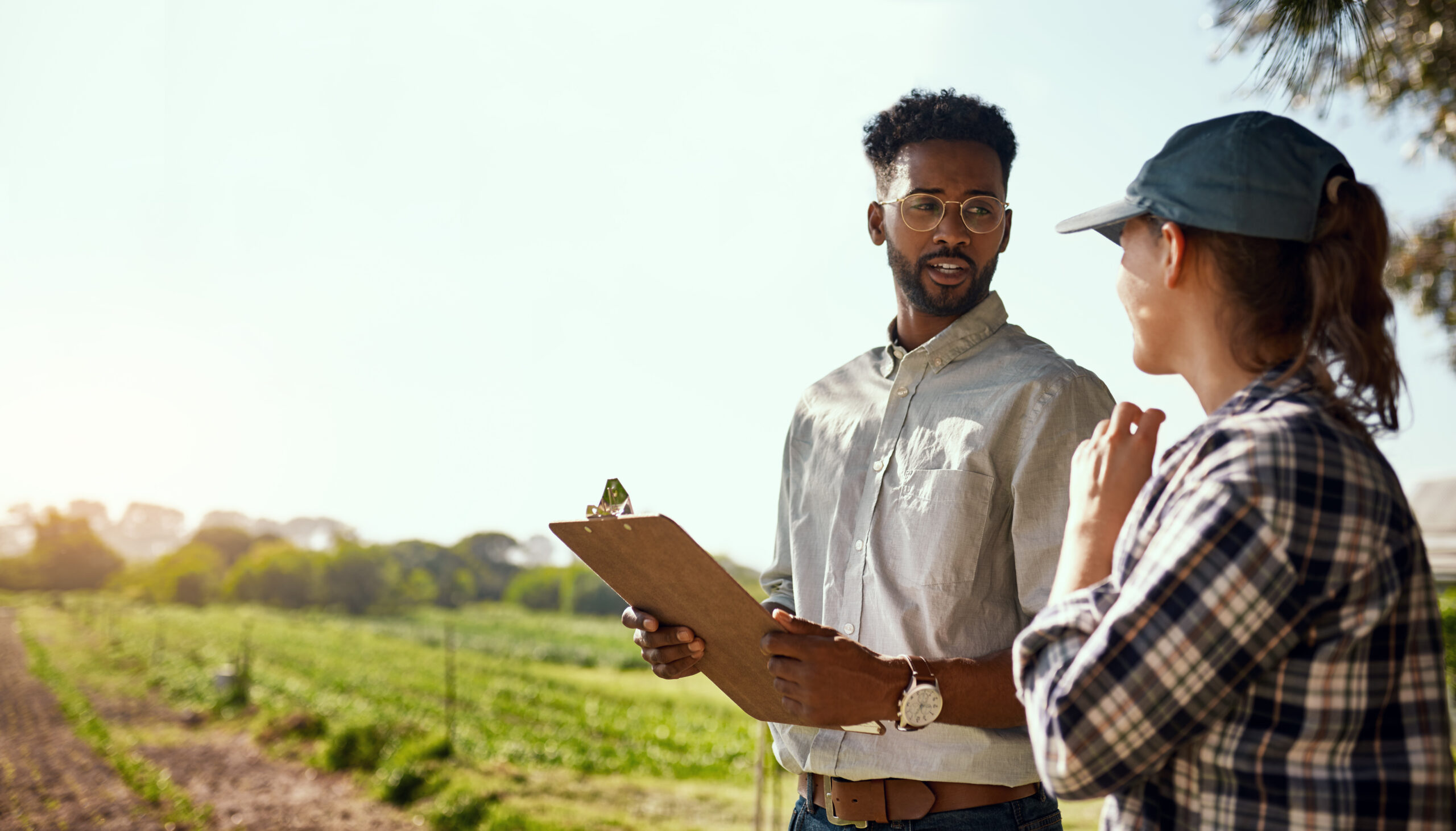 Cropped shot of two young farmers looking over some paperwork while working on their farm