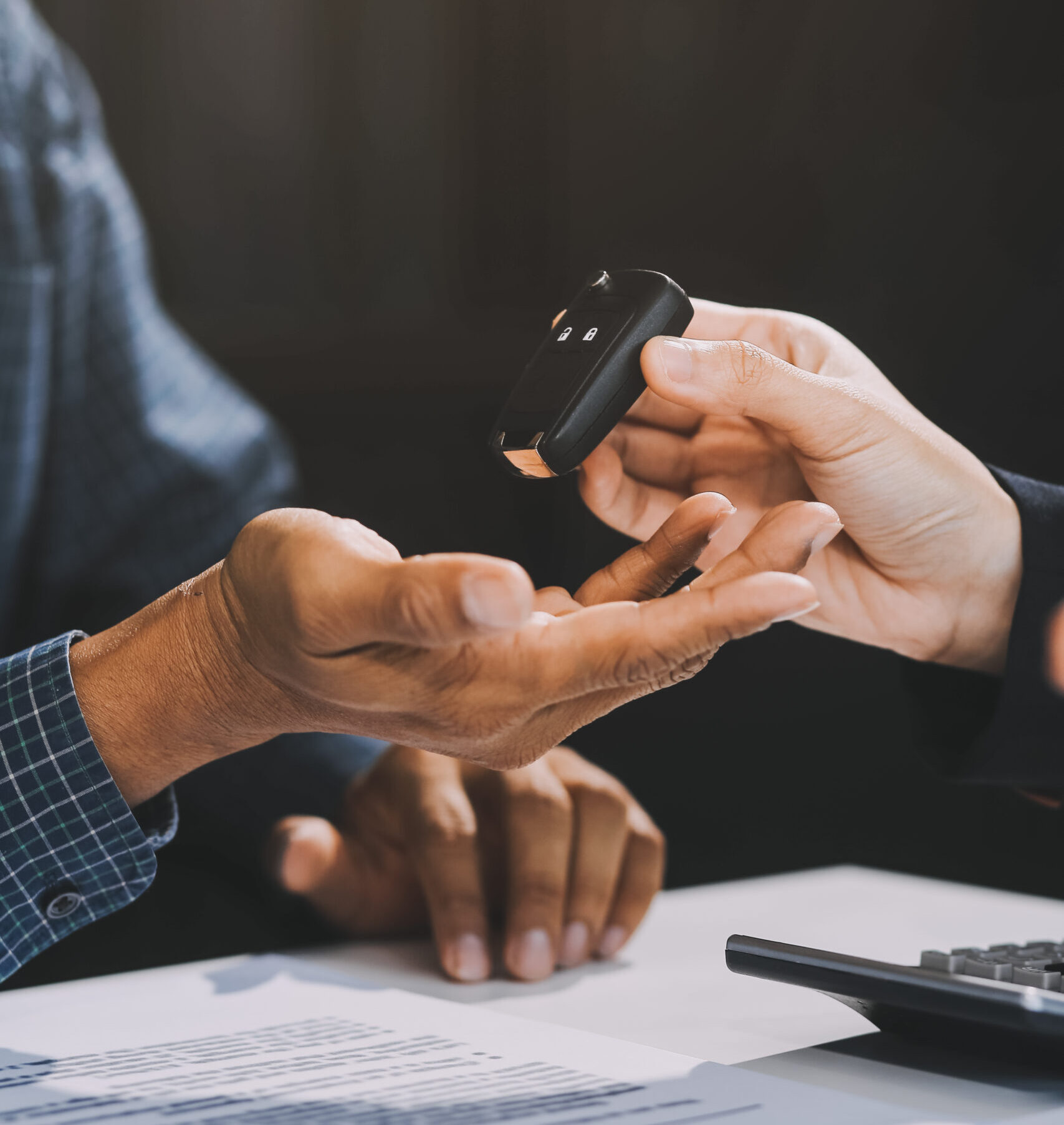 Car sales representative gives keys to new car owner, concept for car rental Focus on the key. Pick up the key. Close-up of the key transfer from the new machine to the buyer.