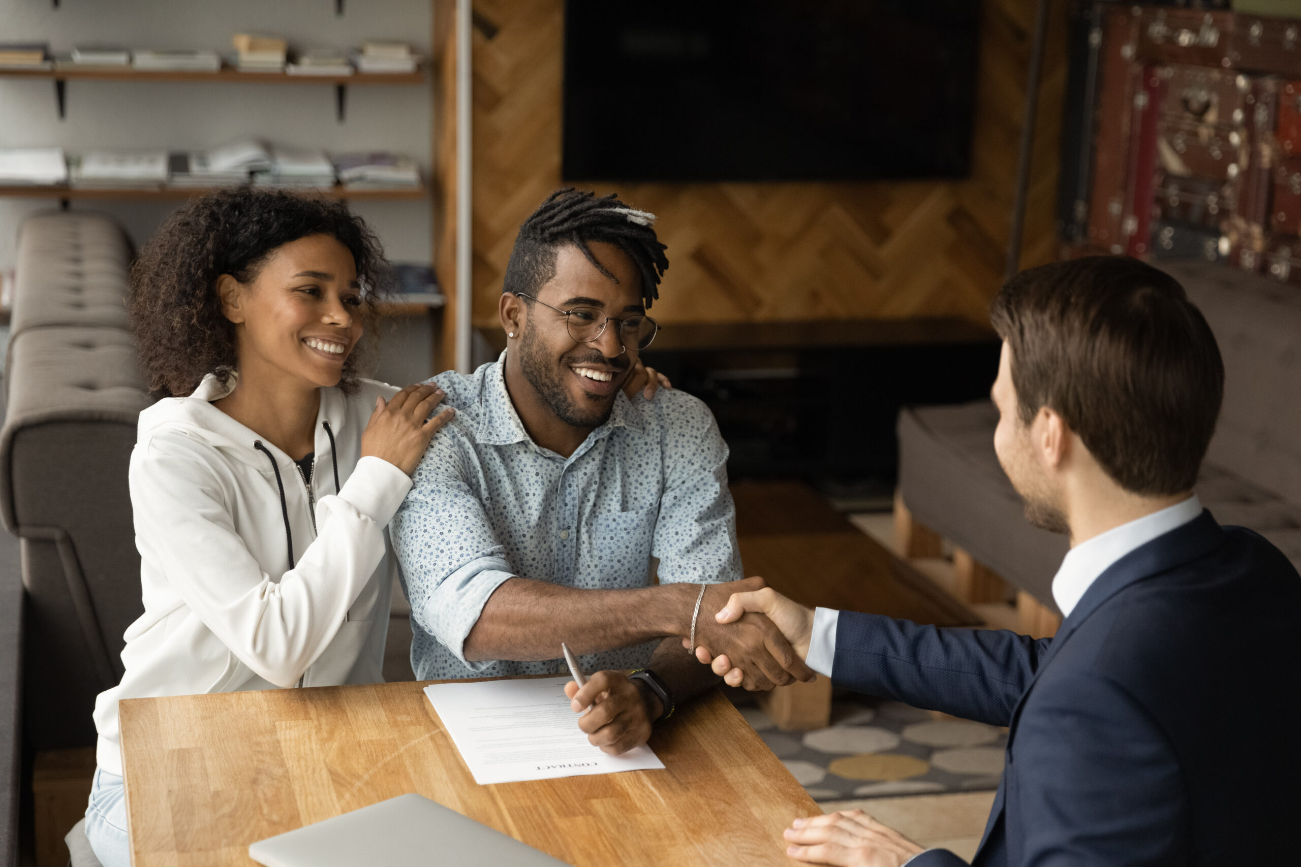 Grateful black family couple handshake with bank manager insurer lawyer thank for consultation before sign contract. Satisfied young african husband wife real estate buyers make deal with male broker